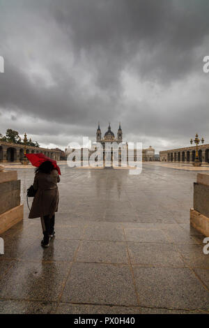 Woman with umbrella walks from Royal Palace to Almudena Cathedral, Madrid, Spain Stock Photo