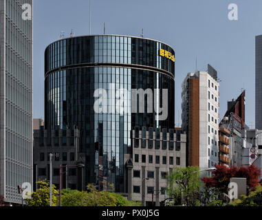 A street level, spring day shot of urban Tokyo, Japan with multi-use towers including the facade of Nakagin Capsule Tower. Stock Photo