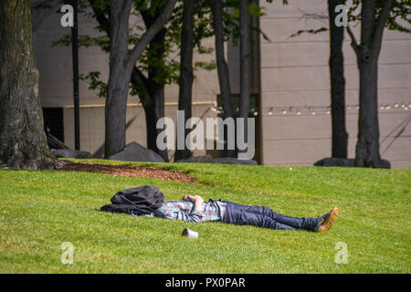 SEATTLE, WASHINGTON STATE, USA - JUNE 2018:  Person laying on the grass in Space needle park in Seattle resting with a coat over his head. Stock Photo
