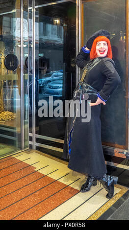 Ms Chaos red haired porter in military chic uniform of black boots coat and hat at QT Hotel Market Street Sydney NSW Australia. Stock Photo