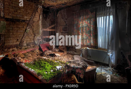 Interior view of room with a bed covered in moss in an abandoned hotel in Germany. Stock Photo