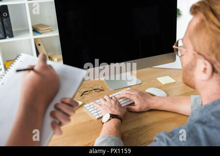 cropped image of father using computer, son holding pen and notebook at home Stock Photo