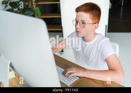 preteen ginger hair boy using computer in room Stock Photo