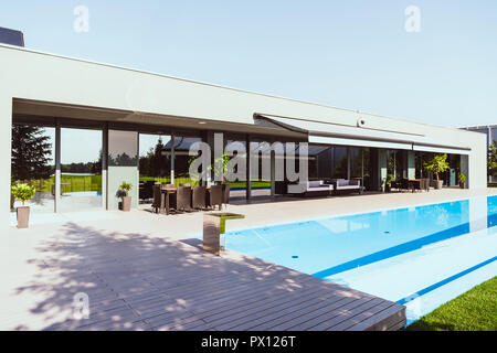 beautiful modern cottage with outdoors swimming pool under clear blue sky Stock Photo