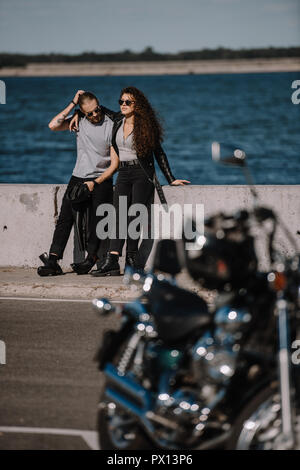 selective focus of young couple with motorcycle on foreground Stock Photo