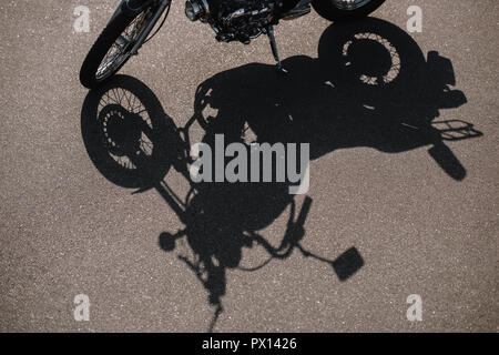 cropped view of motorbike with shadow on asphalt road Stock Photo