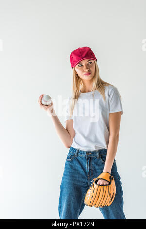 attractive baseball player in red cap holding baseball ball and looking away isolated on white Stock Photo