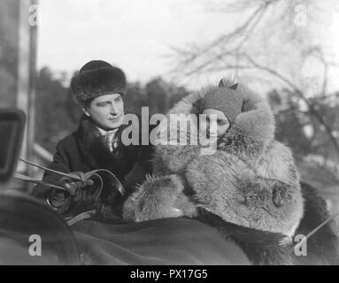 Fur coat in the 1930s. A young couple is sitting together in a horse drawn sledge. The woman is wearing a warm fur coat. Picture from the filming of the movie Charlotte Löwensköld 1930. Stock Photo