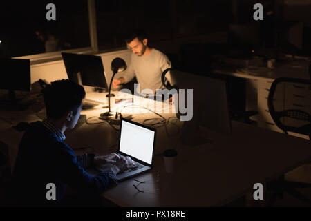 Businessmen working on laptop in office during nighttime Stock Photo