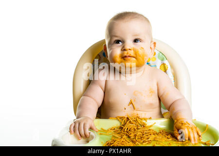 Little baby eating her dinner spaghetti and making a mess on his face Stock Photo