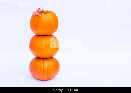 Tower of Three stacked mini pumpkins with fall maple leaf on the top on the white background isolated. Autumn holiday, harvest, Helloween concept. Sel Stock Photo