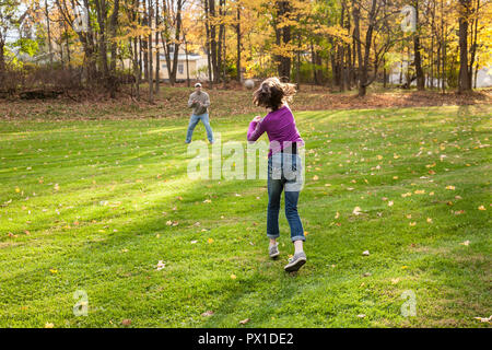 Preteen girl plays baseball catch in backyard with father, Northeast, USA Stock Photo