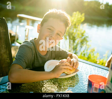 boy eating hamburger outside with his family Stock Photo
