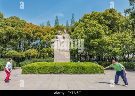Shanghai, China - April 7, 2013: two people exercising badminton in front of marx and engels statue in fuxing park at the city of Shanghai in China on april 7th, 2013 Stock Photo