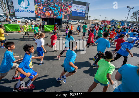 10-year-old multiracial runners pass a Jumbotron video image of themselves as the race begins at a community track event in Costa Mesa, CA. Stock Photo