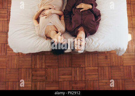Mother and daughter lying on bed and laughing. Woman spending time talking with her elderly mother lying on bed at home. Stock Photo
