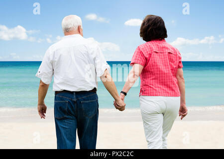 Senior Couple Holding Hands Walking At Beach Stock Photo