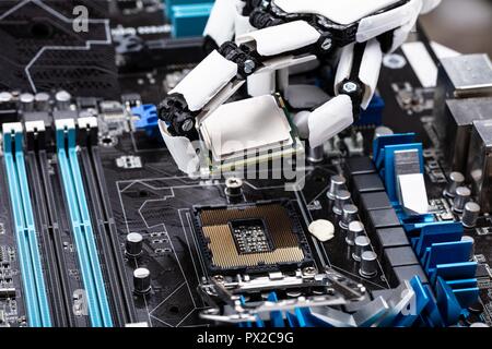 Close-up Of A Robotic Hand Placing Processor Chip In Motherboard Stock Photo