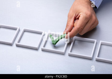 Man's Hand Placing Green Check Mark In Box On Grey Background Stock Photo