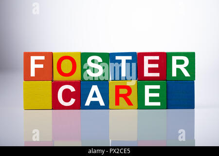 Close-up Of Foster Care Cubic Blocks On Reflective Background Stock Photo