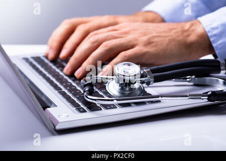 Human Hand Using Laptop With Stethoscope On Keypad Stock Photo