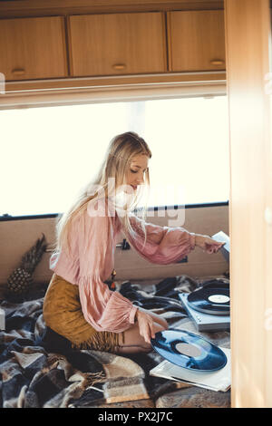 beautiful hippie girl putting vinyl record into player inside camper van Stock Photo