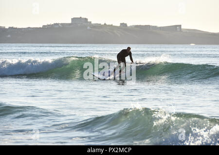 Newquay, Cornwall, England. September 2018. A male paddle boarding across Watergate Bay beach on a sunny afternoon in autumn Stock Photo