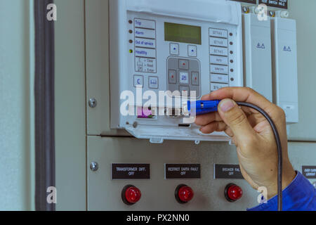 Male engineers are connect cable at equipment to laptop for check electrical system working. Stock Photo