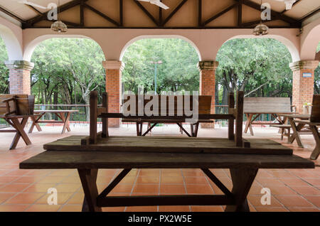 inside the roof of a wooden hut, with brown wooden tables and benches leaning on wooden tables. Stock Photo