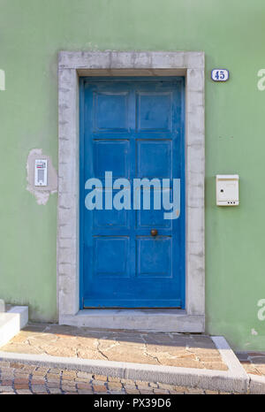 Turquoise front door on a green colored exterior wall Stock Photo