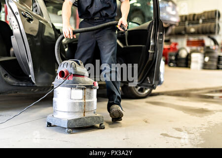 mechanic vacuuming the car at the garage Stock Photo
