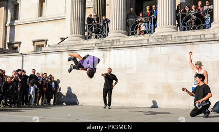 Trafalgar Square, London, UK, 19th Oct 2018. A street performance group called 'OK Worldwide', who have performed together for around 5 years, show off their acrobatic skills to an enthusiastic crowd in Trafalgar Square, bathed in glorious sunshine. The group comprises of members from around Europe who all bring different skills and performance styles. Credit: Imageplotter News and Sports/Alamy Live News Stock Photo