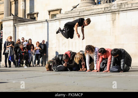 Trafalgar Square, London, UK, 19th Oct 2018. A street performance group called 'OK Worldwide', who have performed together for around 5 years, show off their acrobatic skills to an enthusiastic crowd in Trafalgar Square, bathed in glorious sunshine. The group comprises of members from around Europe who all bring different skills and performance styles. Credit: Imageplotter News and Sports/Alamy Live News Stock Photo