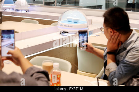 Shanghai. 15th Oct, 2018. Customers take photos of an AGV (automated guided vehicle) robot serving food in a smart restaurant operated by Chinese e-commerce giant Alibaba at the National Exhibition and Convention Center in east China's Shanghai, Oct. 15, 2018. Credit: Fang Zhe/Xinhua/Alamy Live News Stock Photo