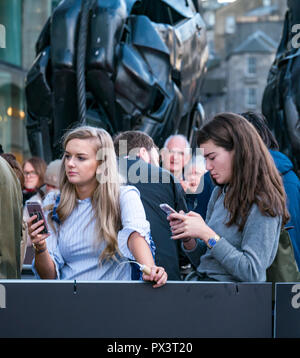 Vue Omni, Leith Walk, Edinburgh, Scotland, United Kingdom, 19th October 2018. Stars attend the Scottish premiere of Netflix Outlaw King. The red carpet is laid out the for the cast and team producing Netflix’s latest blockbuster film, as well as local celebrities. Young female fans look at their phones while they wait for the stars by the giraffe sculptures called Dreaming spires by sculptor Helen Denerley Stock Photo