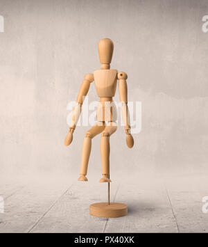 Wooden mannequin posed in front of a greyish background Stock Photo