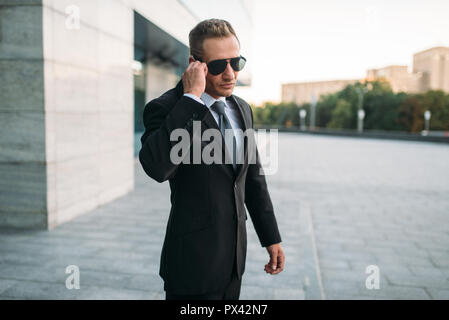 Male bodyguard talking by security earpiece Stock Photo