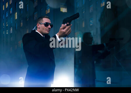 Bodyguard with security earpiece and gun in hands Stock Photo