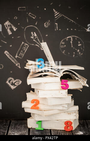 Back to school, stack of books and school supplies on blackboard background painted with chalk, education concept Stock Photo