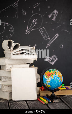 Back to school, stack of books and school supplies on blackboard background painted with chalk, education concept Stock Photo