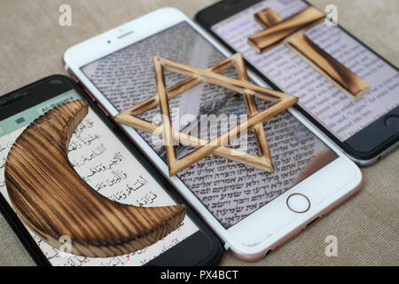 Jewish Star, Christian Cross and and Muslim Crescent, religious symbols of Christianity, Islam, Judaism set on 3 smartphones with digital app. Stock Photo
