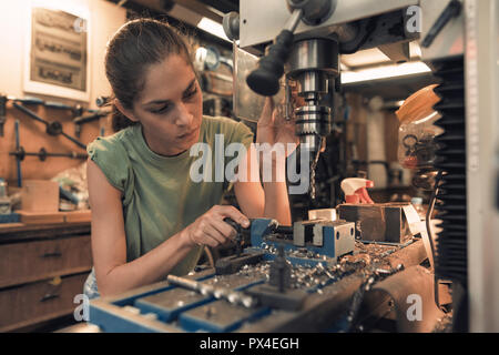 woman mechanic is using a vertical electric dill machine Stock Photo