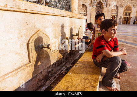 Aleppo, Aleppo Governorate, Syria : Syrian children sit at the fountain in the courtyard of the Great Mosque of Aleppo, the largest and one of the old Stock Photo