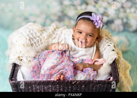 Beautiful smiling baby girl in a busket. Stock Photo