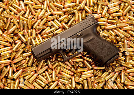 Loaded handgun resting on pile of live ammunition. Stock Photo