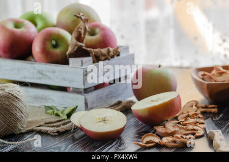 Delicious fresh red apples  and slices of dried apple are on the wooden table. Stock Photo