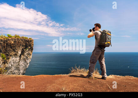 Man photographer with big backpack and camera taking photo of sunset mountains Travel Lifestyle hobby concept adventure active vacations outdoor Stock Photo