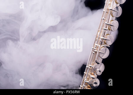 A silver plated alto flute in smoke on a black background Stock Photo