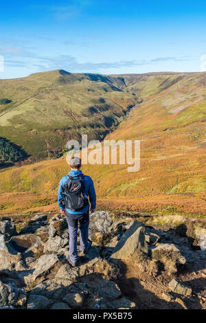 Man in his twenties + Grindslow Knoll and Grindsbrook Clough from Ringing Roger on Kinder Scout in The Peak District National Park, Derbyshire,UK Stock Photo