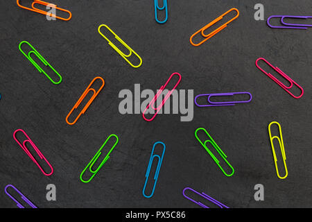 Colorful paperclips stationery abstract on dark background Stock Photo